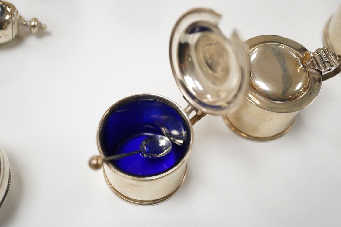 A George V silver mustard pot, London, 1931, with blue glass liner and associated silver shovel, together with a George V silver pepperette, a pair of small silver mustard pots and spoons, a pair of small silver pepperet
